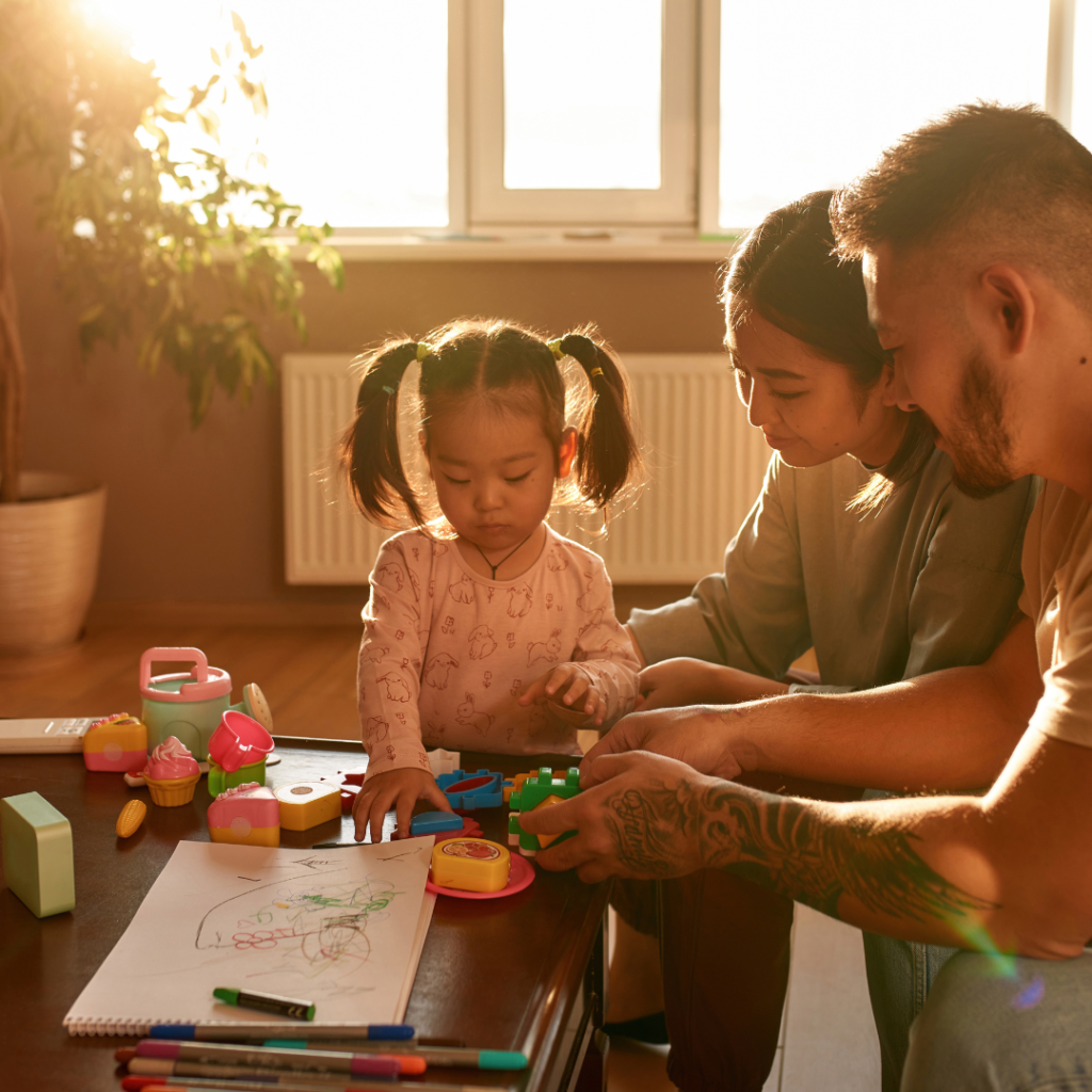 Parents playing with toddler at coffee table.